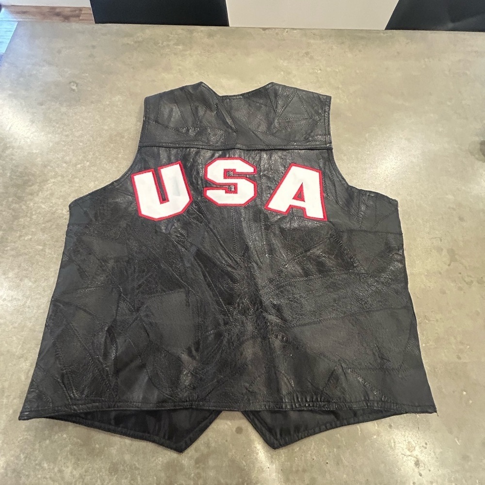 Leather patchwork vest with embroidered U.S.A patches on back. Snap closure.